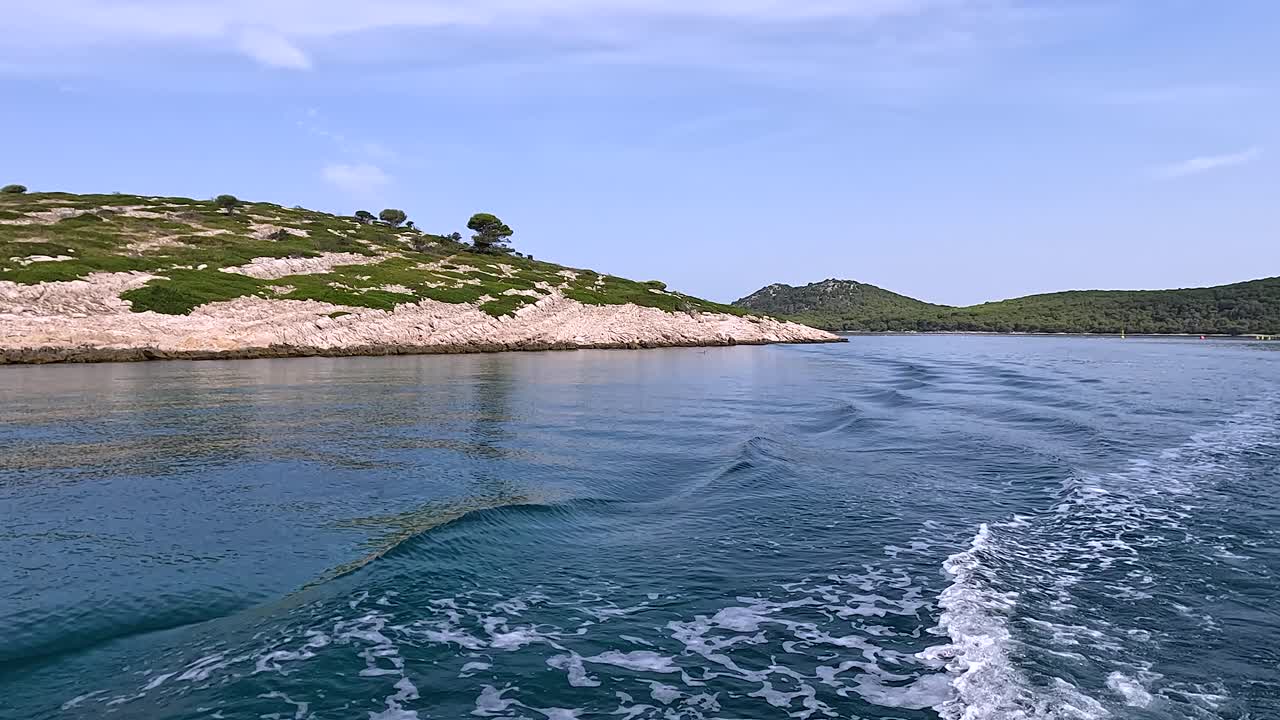 Scenic boat sailing along a rocky coastline of Croatian island near fish farm in Adriatic sea