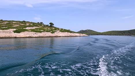 scenic boat sailing along a rocky coastline of croatian island near fish farm in adriatic sea