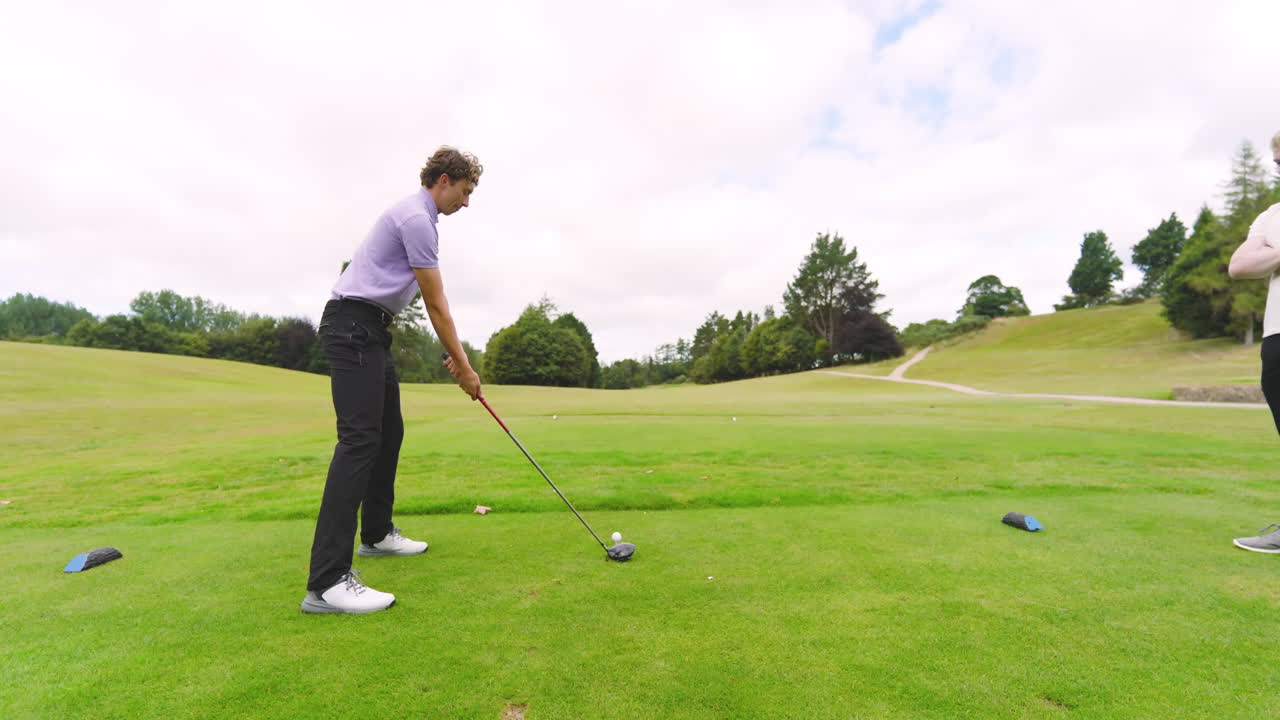 Male golf players playing golf, one player knocks golf ball out on golf course, copy space