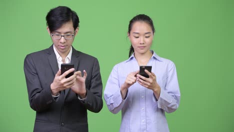 young asian business couple using phone together