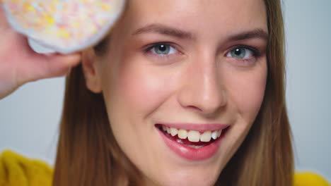 Mujer-Sonriente-De-Cerca-Divirtiéndose-Con-Donuts-En-La-Cámara-Sobre-Fondo-Gris.