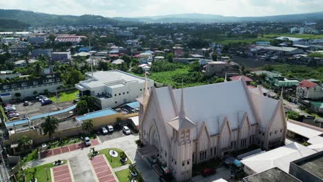 cinematic flyover drone shot of white, pristine church located in bustling, provincial town