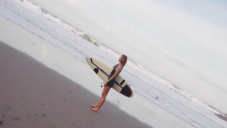 Schöne-Sportliche-Frau,-Die-Ihr-Surfbrett-An-Einem-Sandstrand-Hält