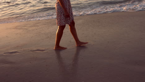 Woman-walking-on-beach-during-sunset