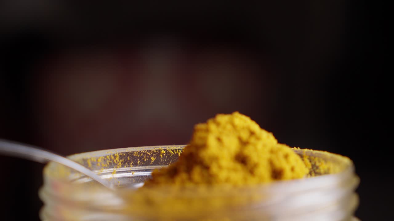Jar of Curcuma spice ingredient, spoonful of powder, food aroma and taste