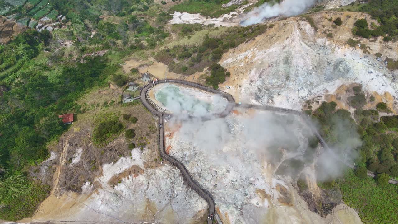 Aerial panorama of Sikidang Crater in Dieng, Indonesia, capturing the geothermal pool, rising steam, and scenic volcanic landscape on a sunny day