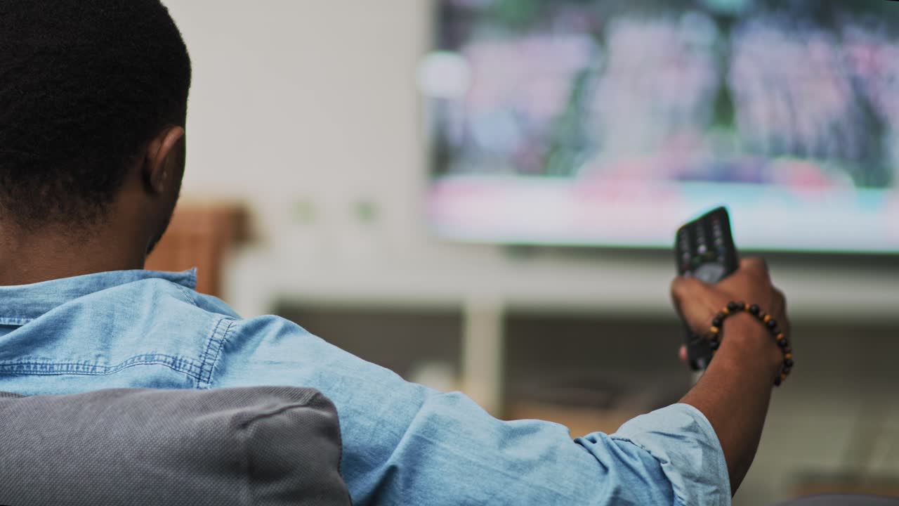 Video ripreso da dietro di un uomo che guarda la TV