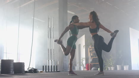 stretching leg, two women in gym wearing sportswear, preparing for workout