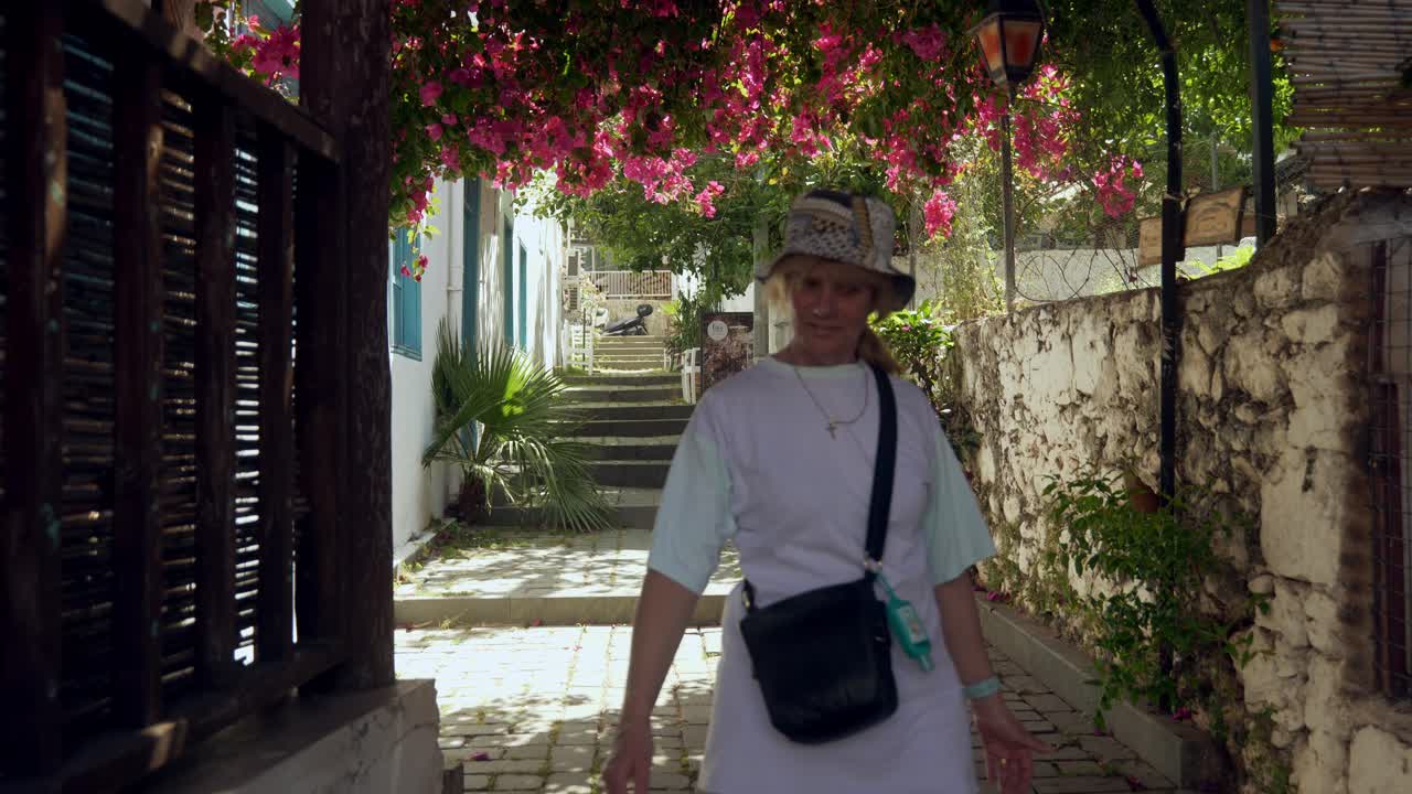 Female tourist explores narrow cobbled streets of Kas Mediterranean town.