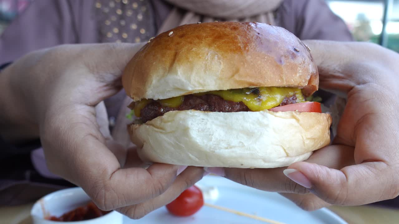 primer plano de una jugosa hamburguesa con queso en la mano de alguien
