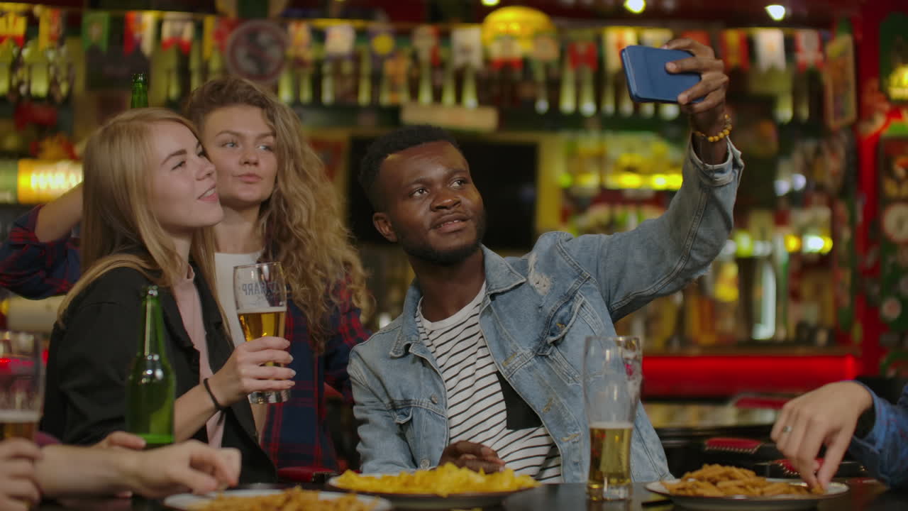 Gruppo di giovani amici che bevono e ridono in un bar.