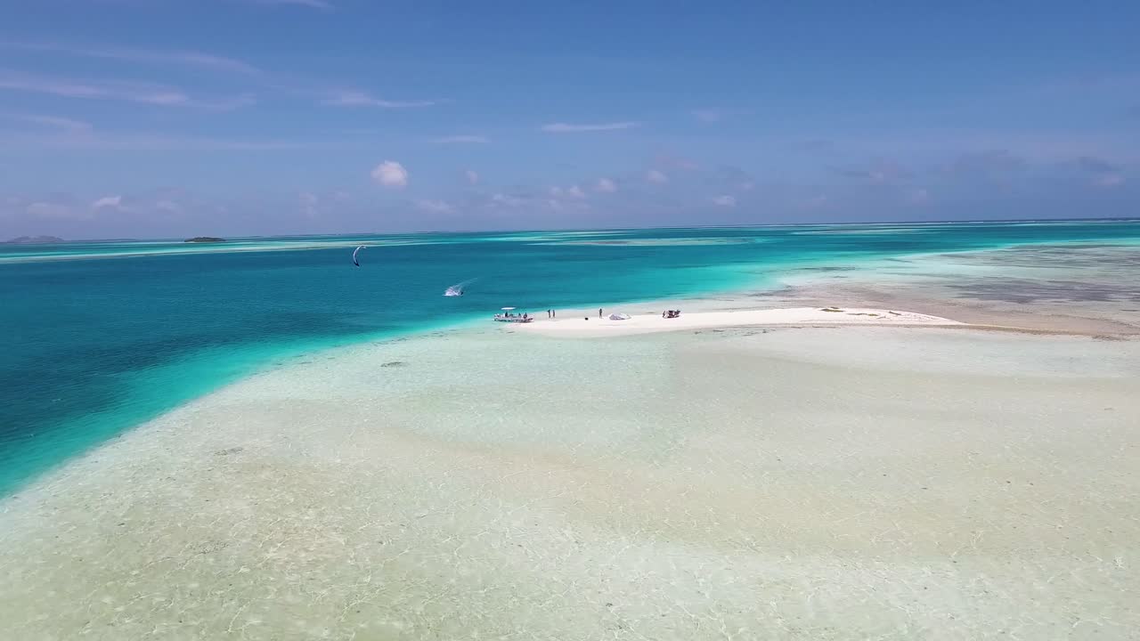 enfoque aéreo banco de arena con gente disfruta y hombre salta kitesurf, los roques