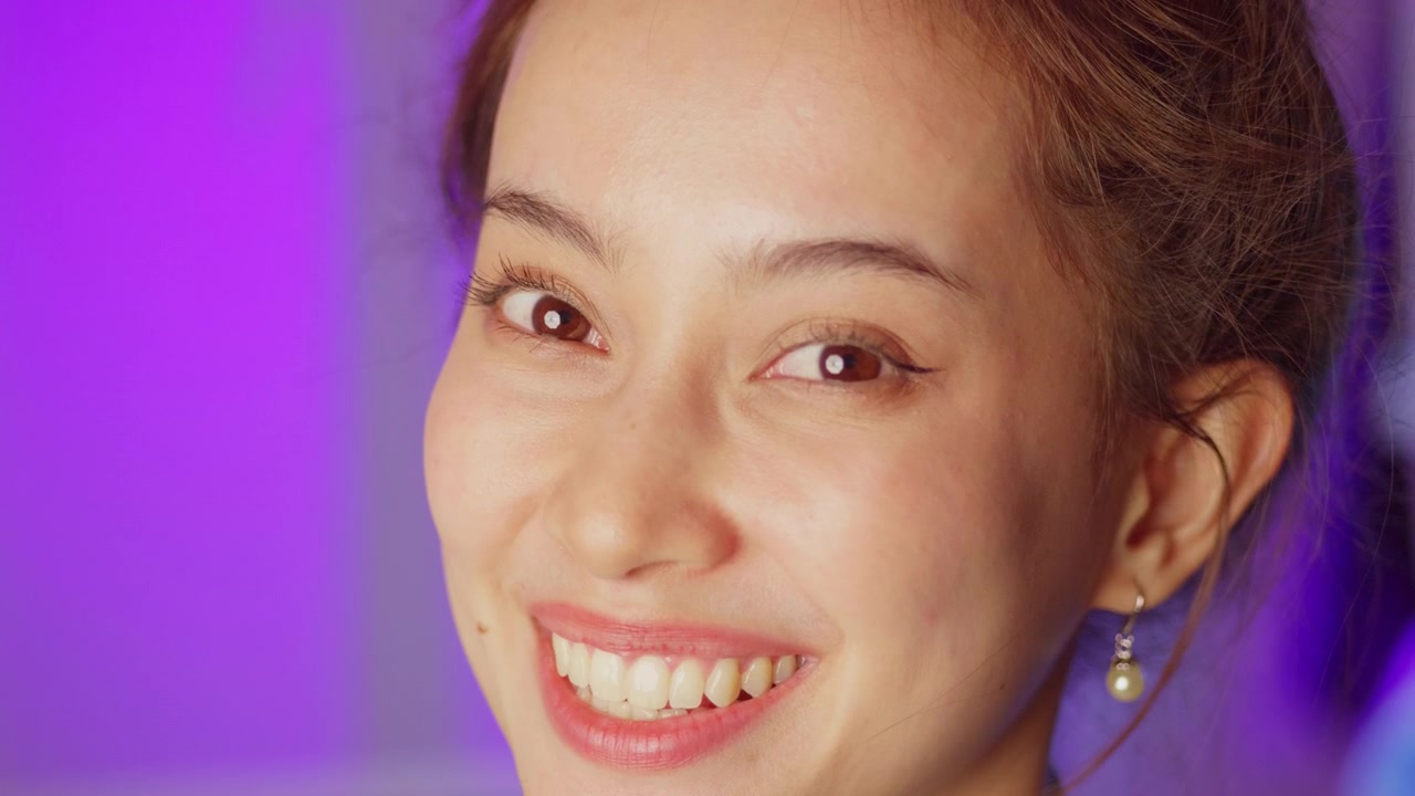 Un ritratto ravvicinato di una donna gioiosa con illuminazione vivace che esprime positività e calore, perfetto per i social media.