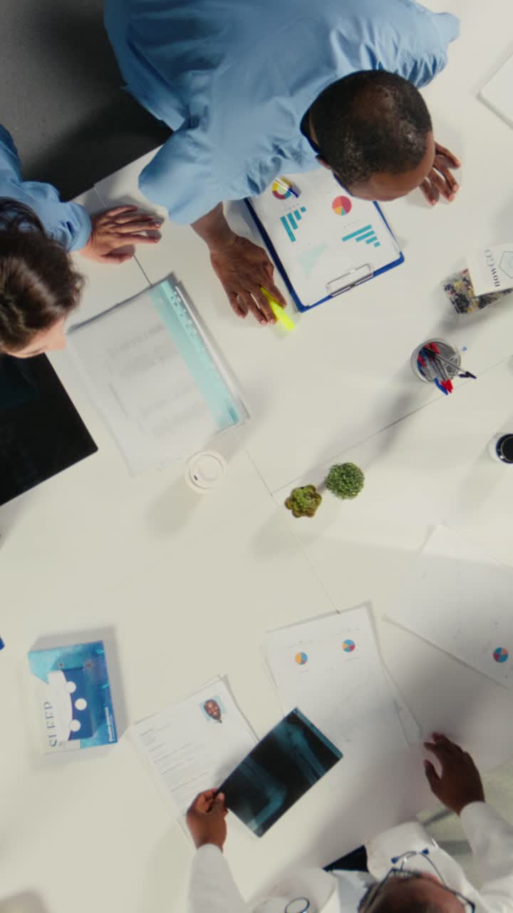 Video verticale. Vista dall'alto con zoom indietro del personale medico che partecipa a una discussione clinica