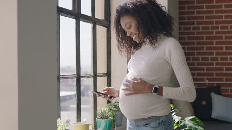 mujer afroamericana embarazada feliz usando un teléfono inteligente compartiendo el estilo de vida de la maternidad en las redes sociales sonriendo disfrutando de la comunicación por teléfono móvil navegando por mensajes bebiendo café en un apartamento