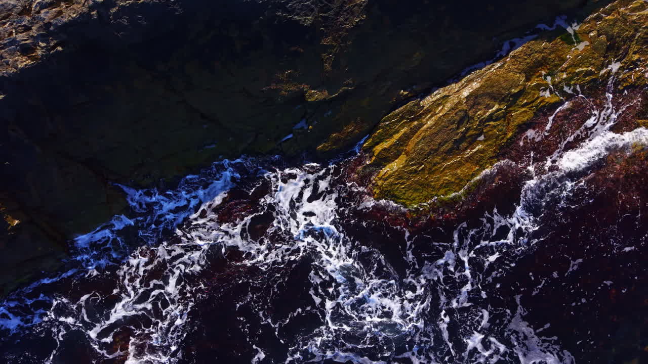 Captivating waves crash against rugged rocks at sunrise along the tranquil coastline