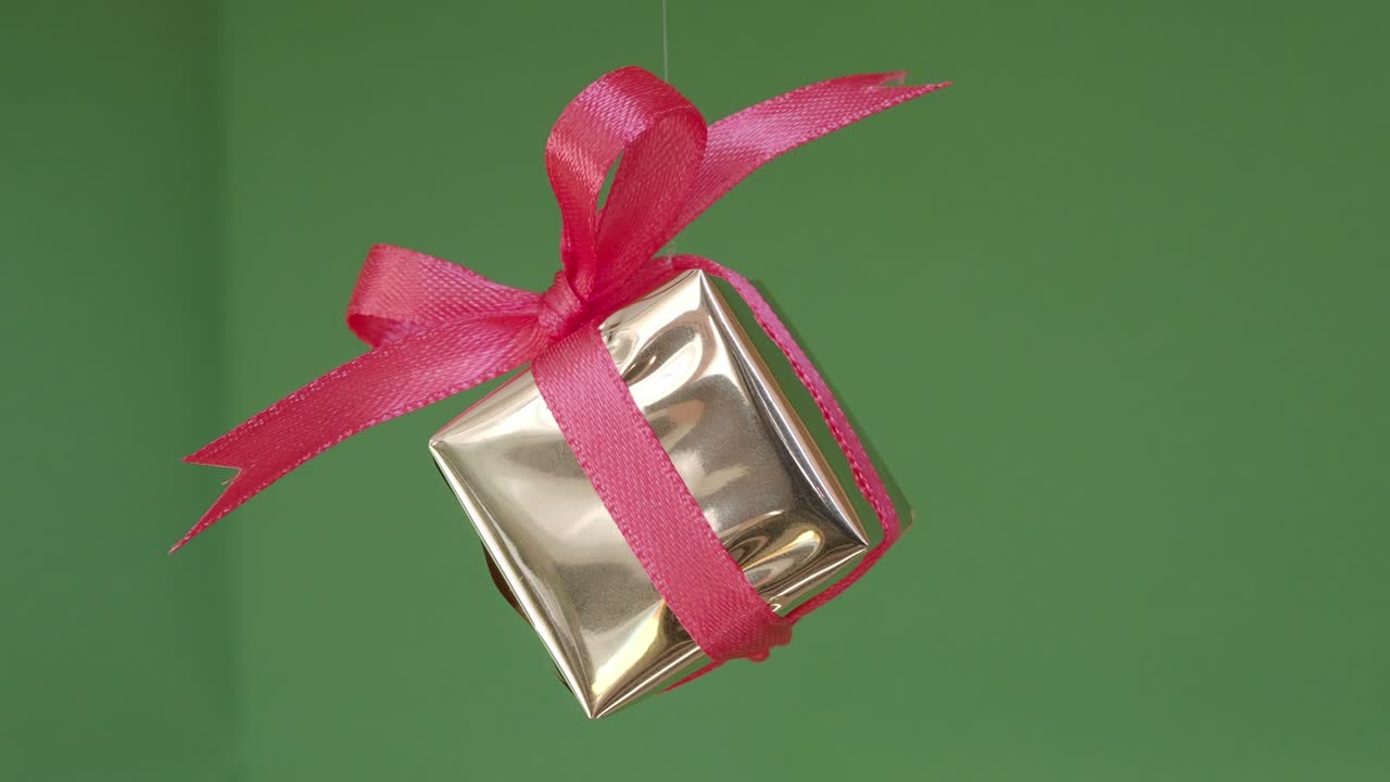 caja de regalos con cinta roja girando sobre fondo verde. rotación de 360 grados