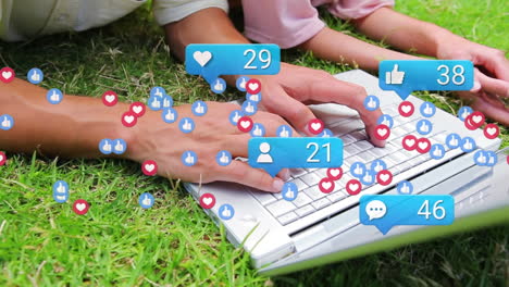 Animation-Von-Social-Media-Symbolen-über-Dem-Mittelteil-Von-Mutter-Und-Tochter,-Die-Im-Garten-Einen-Laptop-Benutzen