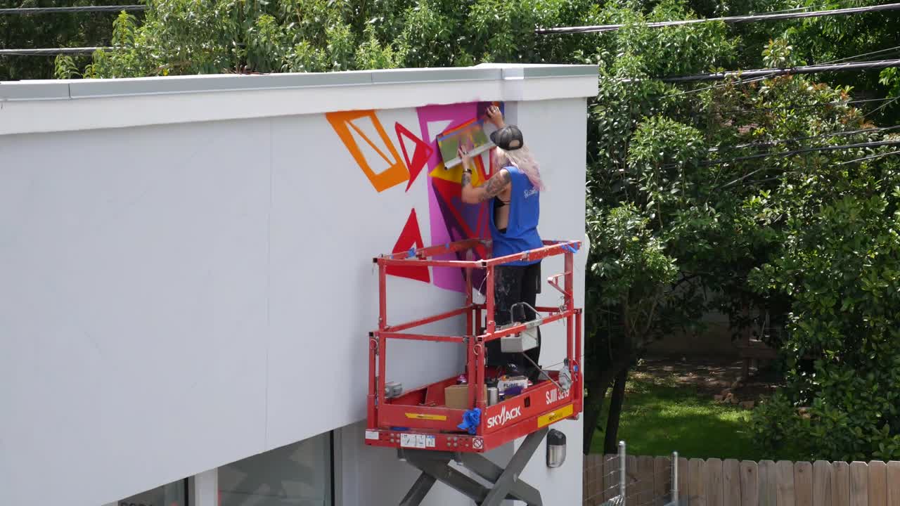 muralista femenina pintando con spray coloridos grafitis en la pared