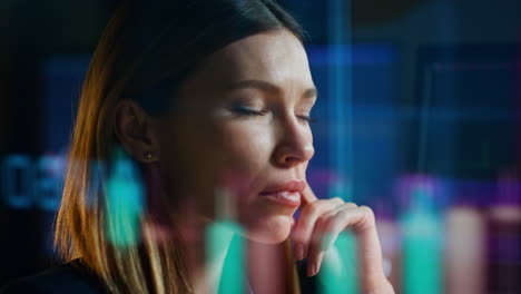 Closeup-woman-analysing-stock-market-data-in-hologram-reflection-in-dark-office.