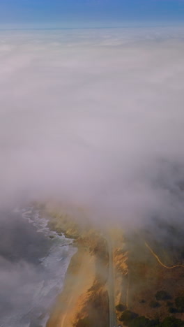 pacific coastline covered with thick white fog. rocky beach of montara, california, usa. aerial view. vertical video