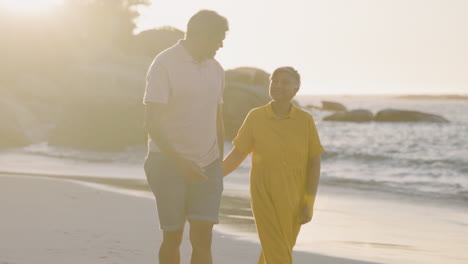 Senior-couple,-beach-and-holding-hands-on-walk