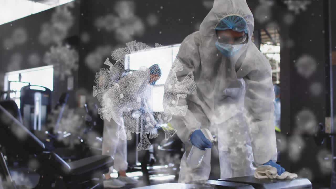 여러 개의 코로나19 세포가 소독제를 사용하여 체육관을 청소하는 보건 노동자 그룹 위에 떠다니고 있습니다.