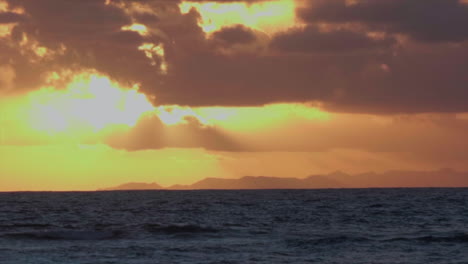 sunset through clouds over tropical ocean horizon