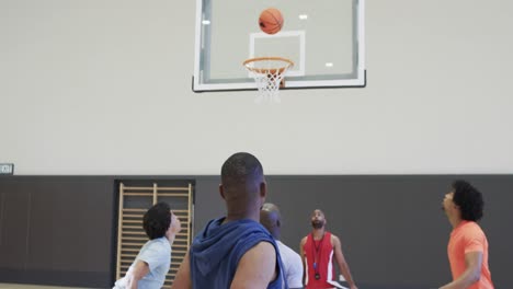 Diverse-male-basketball-players-in-action-during-game-at-indoor-court,-slow-motion