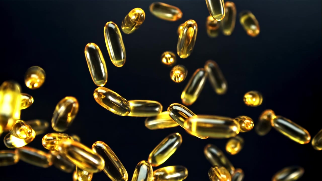 Capsule dorate di Omega 3 che cadono al rallentatore.