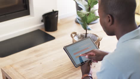 A-young-African-American-man-examines-smart-home-app-energy-usage-on-a-tablet