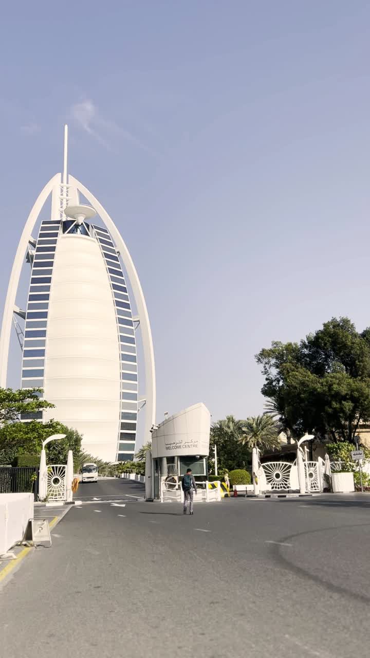 Esterno iconico dell'Hotel Burj Al Arab con una persona che cammina a Dubai.