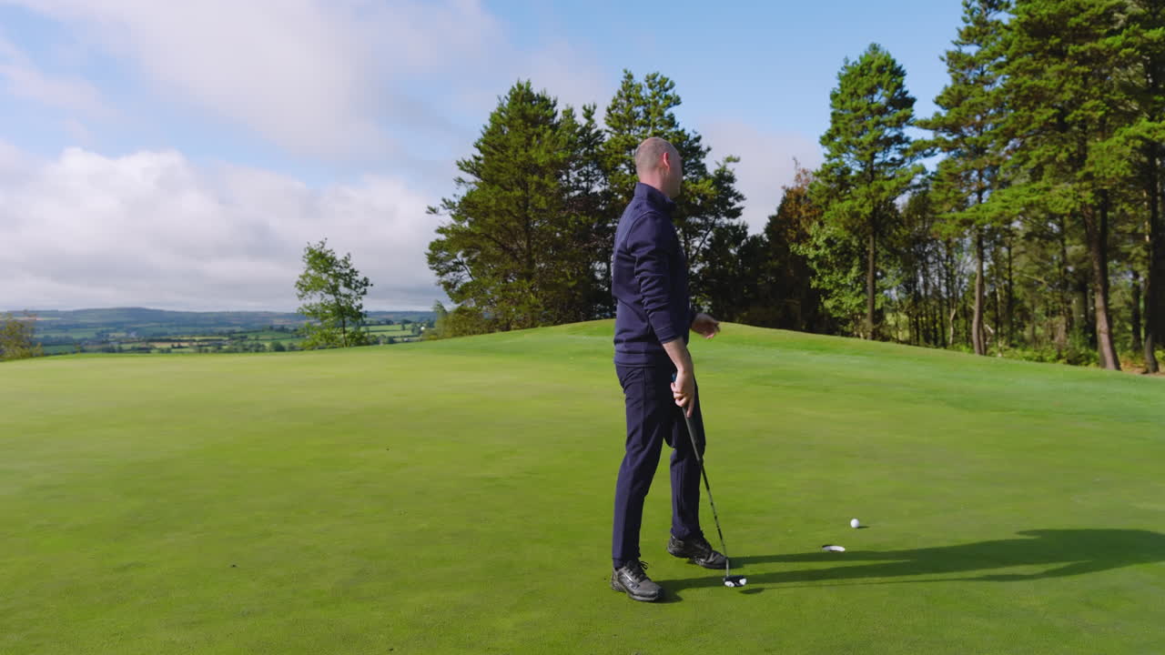 Male golf player playing golf and knocking golf ball into cup on golf course, copy space