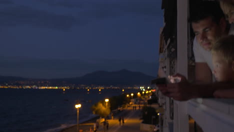 En-La-Ventana,-Familia-Viendo-Fotos-En-Una-Tableta-En-La-Ciudad-De-Perea,-Grecia