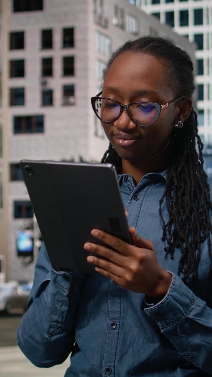 Vertical Video Smiling african american woman using tablet and walking in the city center