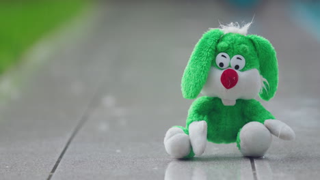 a plush hare sits in the pouring rain on a garden path