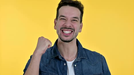 retrato de un joven celebrando el éxito, fondo amarillo