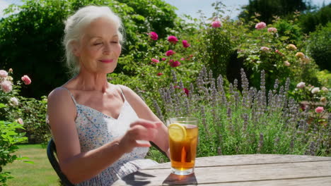 senior woman enjoying a refreshing beverage in a sunny garden