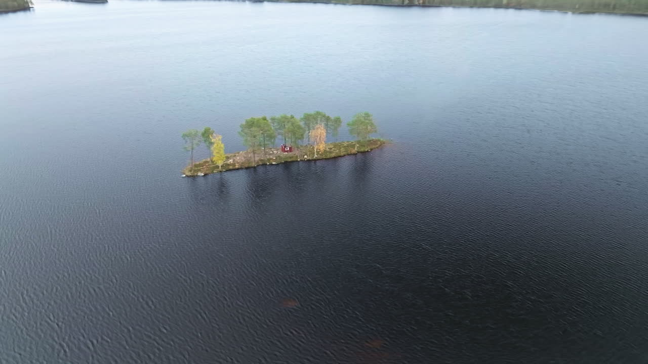 cabaña de madera roja con árboles de otoño en un islote rodeado de un lago en suecia