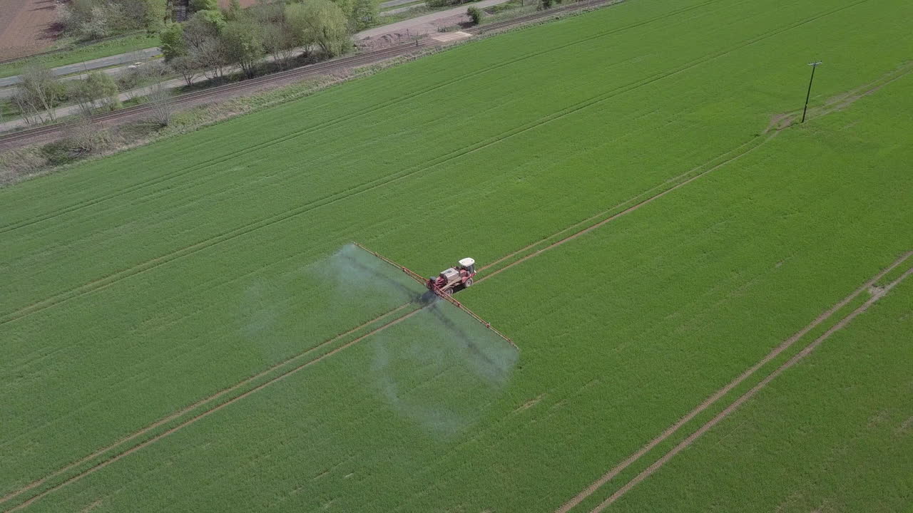 vista aérea de un granjero rociando cultivos en un campo en aberdeenshire en un día soleado, escocia