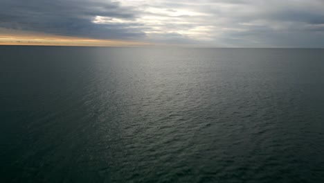 Aerial-view-of-a-sea-water-background-and-sun-reflections-during-sunrise-Aerial-flying-drone-view