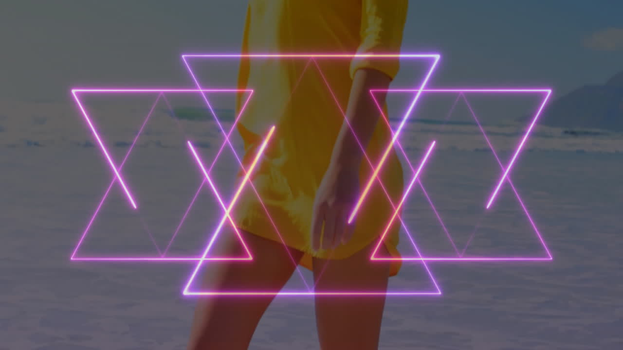 Neon pink triangle animation over person in yellow dress at beach