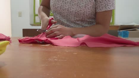 dolly in shot of a latin seamstress cutting and adjusting a dress