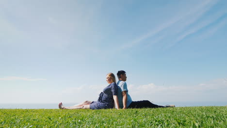 multi-ethnic couple resting on the green grass admiring the beautiful nature