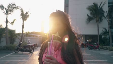 brunette with watermelon drink stands at back sunshine