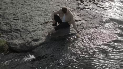 paper boat on river. origami ship sailing on pond. man hand launch paper boat on water and pushing it away. handsome man launching origami ship in water.