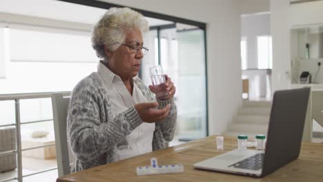 african american senior woman medicine in front of laptop at home