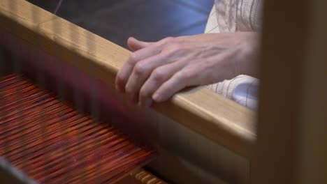 woman works on a traditional loom making a scarf