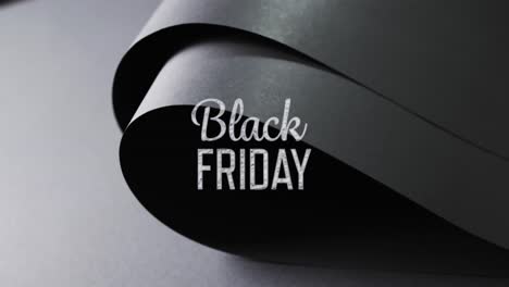 Animation-Von-Black-Friday-Text-über-Aufgerolltem-Schwarzem-Papier-Auf-Grauem-Hintergrund