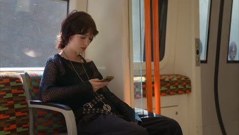 shot of alternative style woman using mobile phone sitting on london underground train in real time